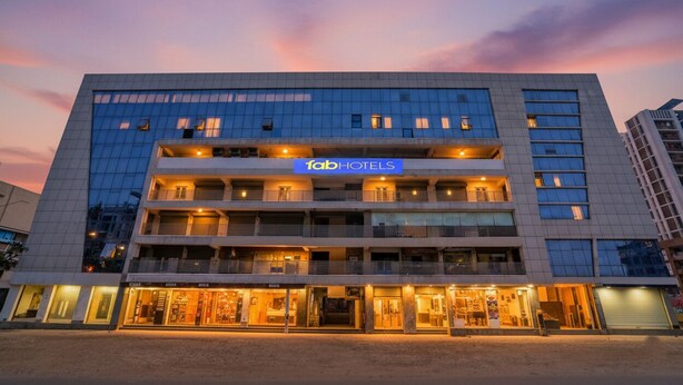 Ein mehrstöckiges Hotel mit einem gut sichtbaren 'fabHOTELS'-Schild, das ein modernes architektonisches Design mit Balkonen und einem Ladenbereich im Erdgeschoss aufweist.