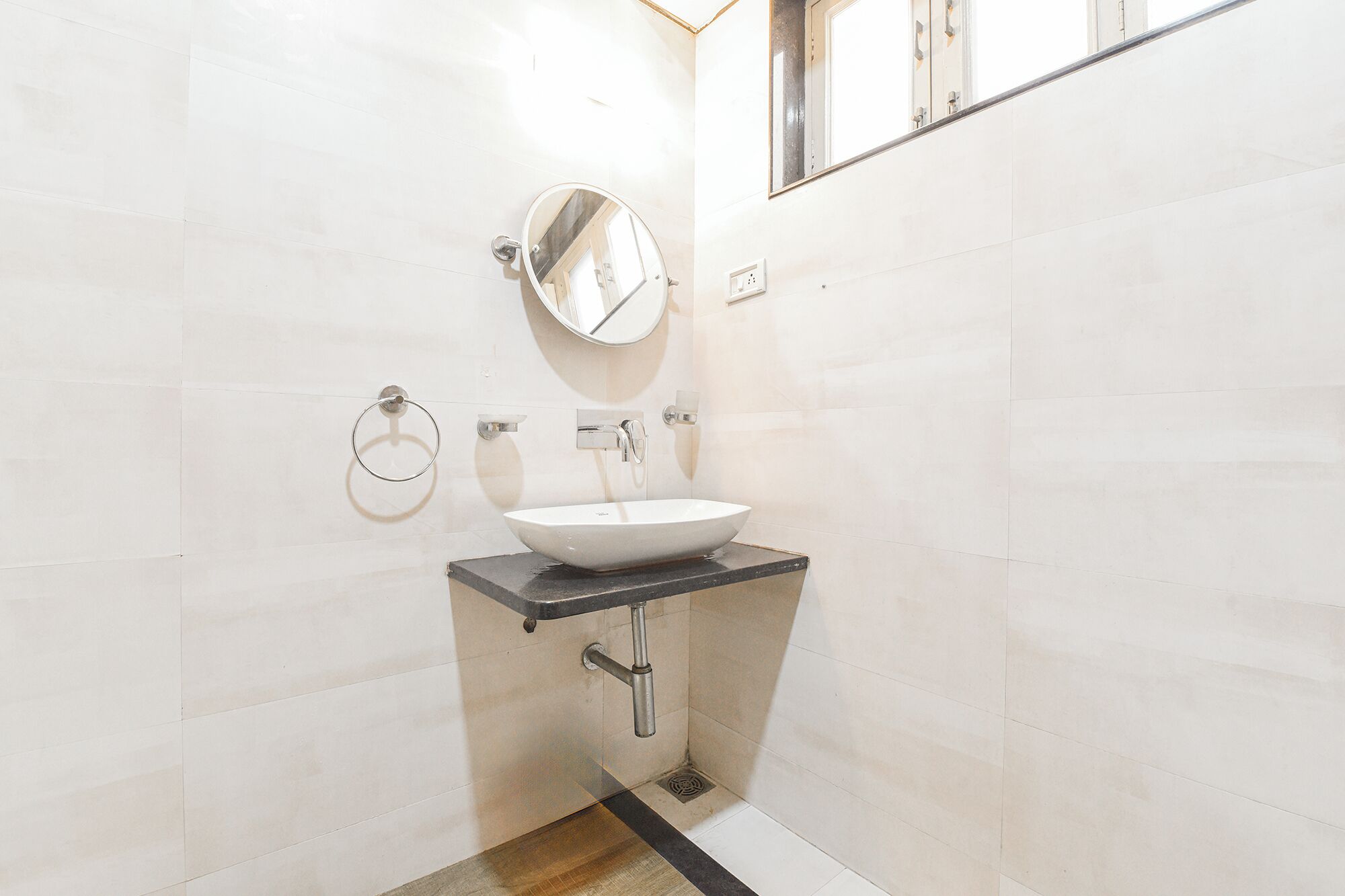 Ein Badezimmer mit einem weißen Waschbecken, einem Spiegel und einem Handtuchhalter an der Wand.