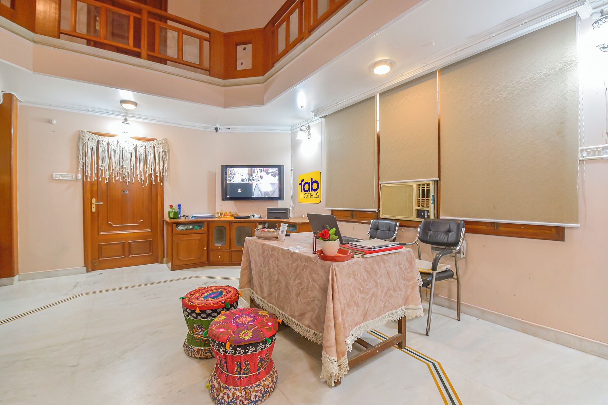 A hotel room with a wooden staircase, a television, a desk with a laptop, and a large mirror.