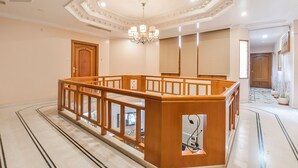 Un'ampia hall d'albergo con pavimento in marmo, una reception in legno e un lampadario.