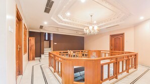 Spaziosa hall d'albergo con una reception in legno, un lampadario e una scala che conduce a un piano superiore.