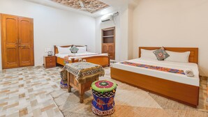Una camera da letto con due letti, un'armadietto in legno, un tavolino e uno sgabello decorativo.