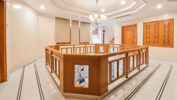 Un'hall dell'hotel con una scrivania in legno all'accoglienza, un lampadario e un'ampia porta in legno.