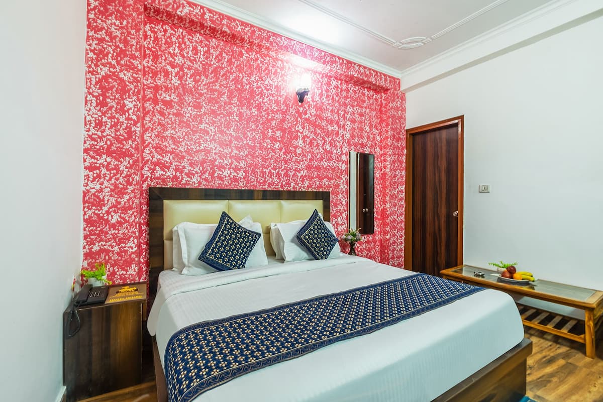 A neatly arranged bedroom with a bed, bedside tables, a mirror, and a wooden door.