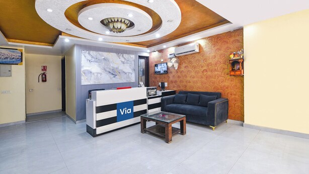A reception area with a marble wall, a reception desk, a sofa, and a small table. - Via Diamond Key (New Delhi)