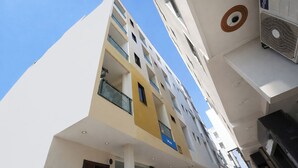 A multi-story building with balconies, a visible air conditioning unit, and a clear blue sky. - Via Diamond Key (New Delhi)