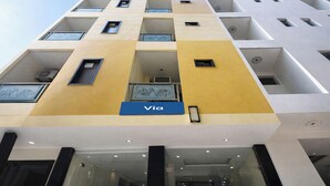 A multi-story building with a yellow and white facade, a visible 'Via' sign, and a glass entrance. - Via Diamond Key (New Delhi)