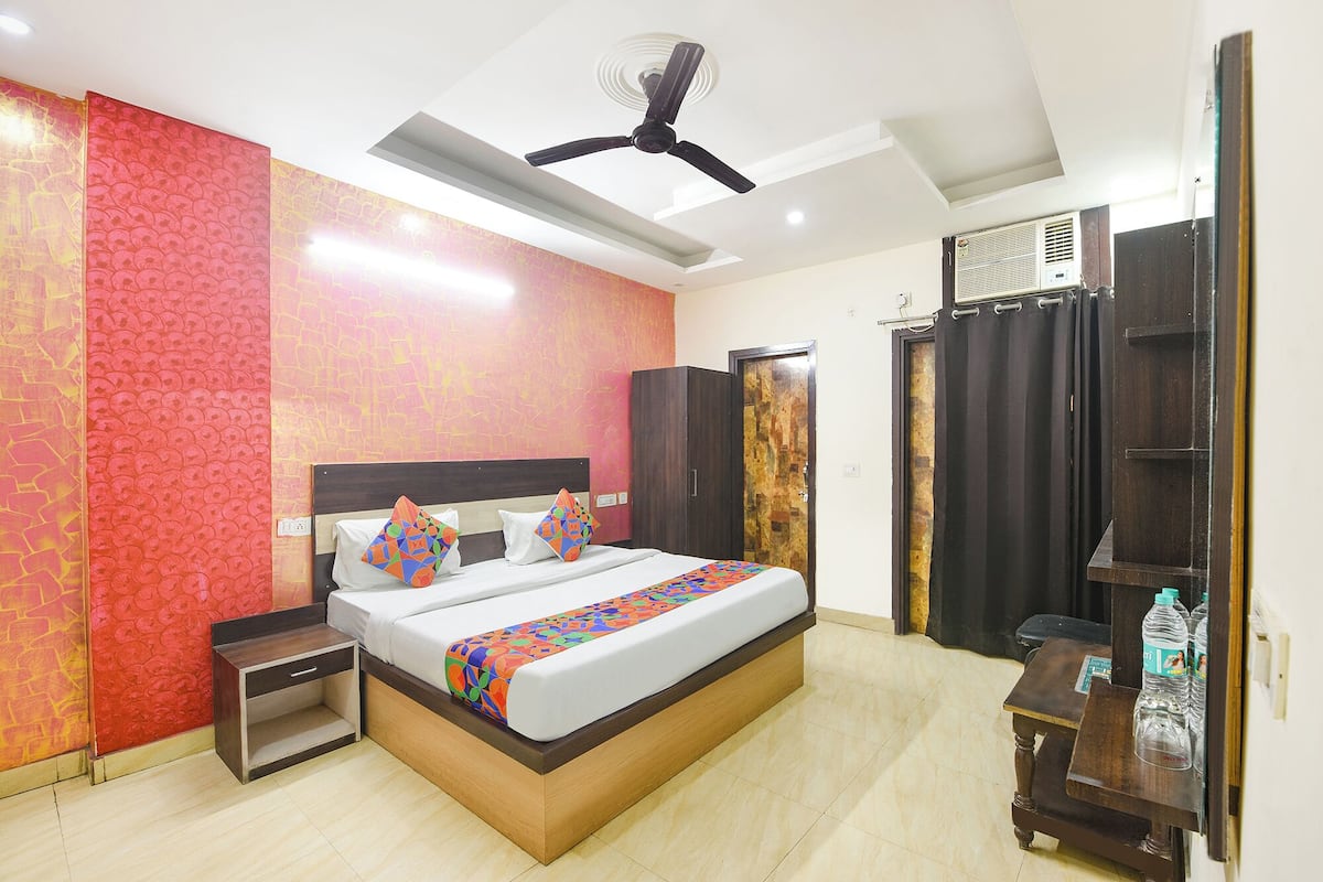 A hotel room with a bed, a nightstand, a wardrobe, a ceiling fan, and an air conditioning unit.