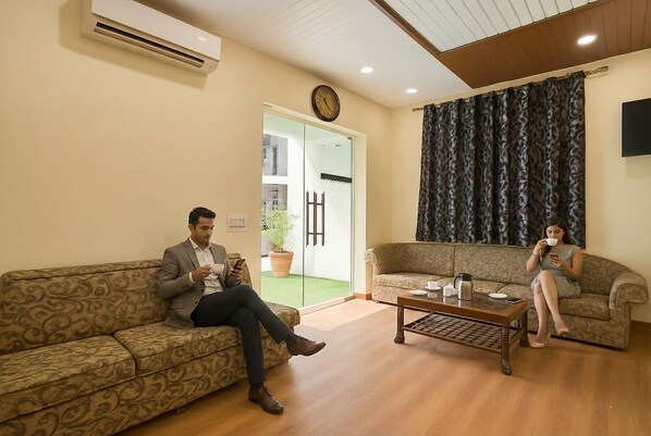 A living room with two patterned sofas, a coffee table, and a clock on the wall.