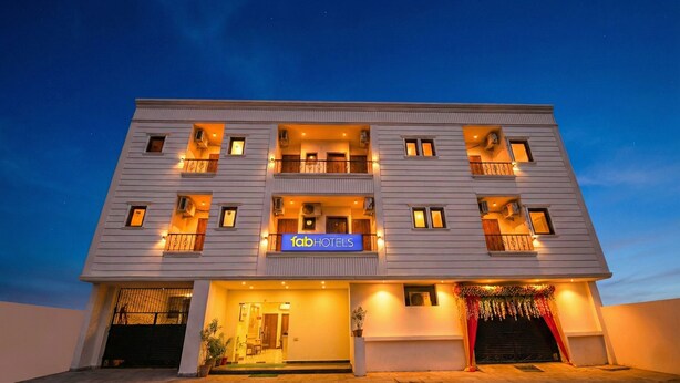 Un immeuble à plusieurs étages, avec une enseigne « fab hotels » au rez-de-chaussée, des balcons à chaque étage et une entrée fermée par un portail.