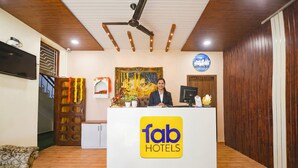 Un comptoir d’accueil orné du logo de « fab hotels », un ventilateur de plafond, un téléviseur et un tableau encadré accroché au mur.