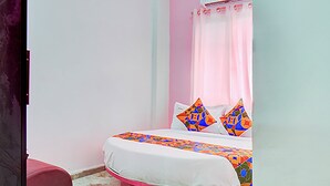 A bedroom with a pink bed, white bedding, and colorful pillows. - Via Pink House (Pune)