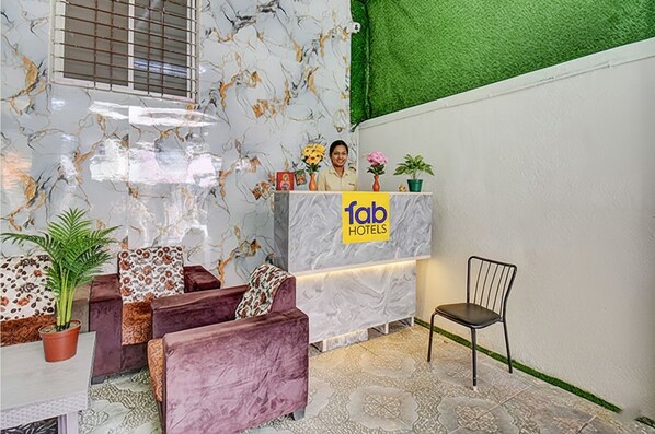 A reception area with a marble counter, plush seating, and a green wall. - Via Pink House (Pune)