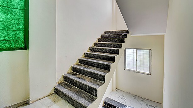 A staircase with dark steps leading to a landing. - Via Pink House (Pune)