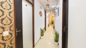A hallway with doors numbered 101, potted plants, and a ceiling light fixture. - Fabhotel Lotus Inn (Faridabad)