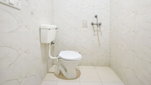 A small, white bathroom with a toilet and a shower. - Fabhotel Lotus Inn (Faridabad)