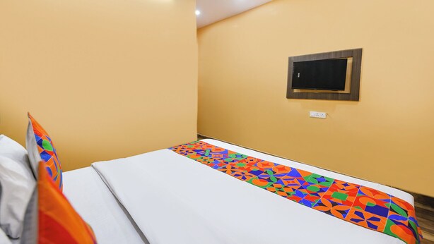 A room with a bed, a small TV mounted on the wall, and a ceiling light. - Fabhotel Lotus Inn (Faridabad)