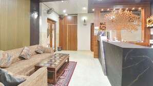 A modern hotel lobby with a wooden reception desk, a sofa, and a patterned rug. - Fabhotel Sunroof & Rooftop (Jaipur)