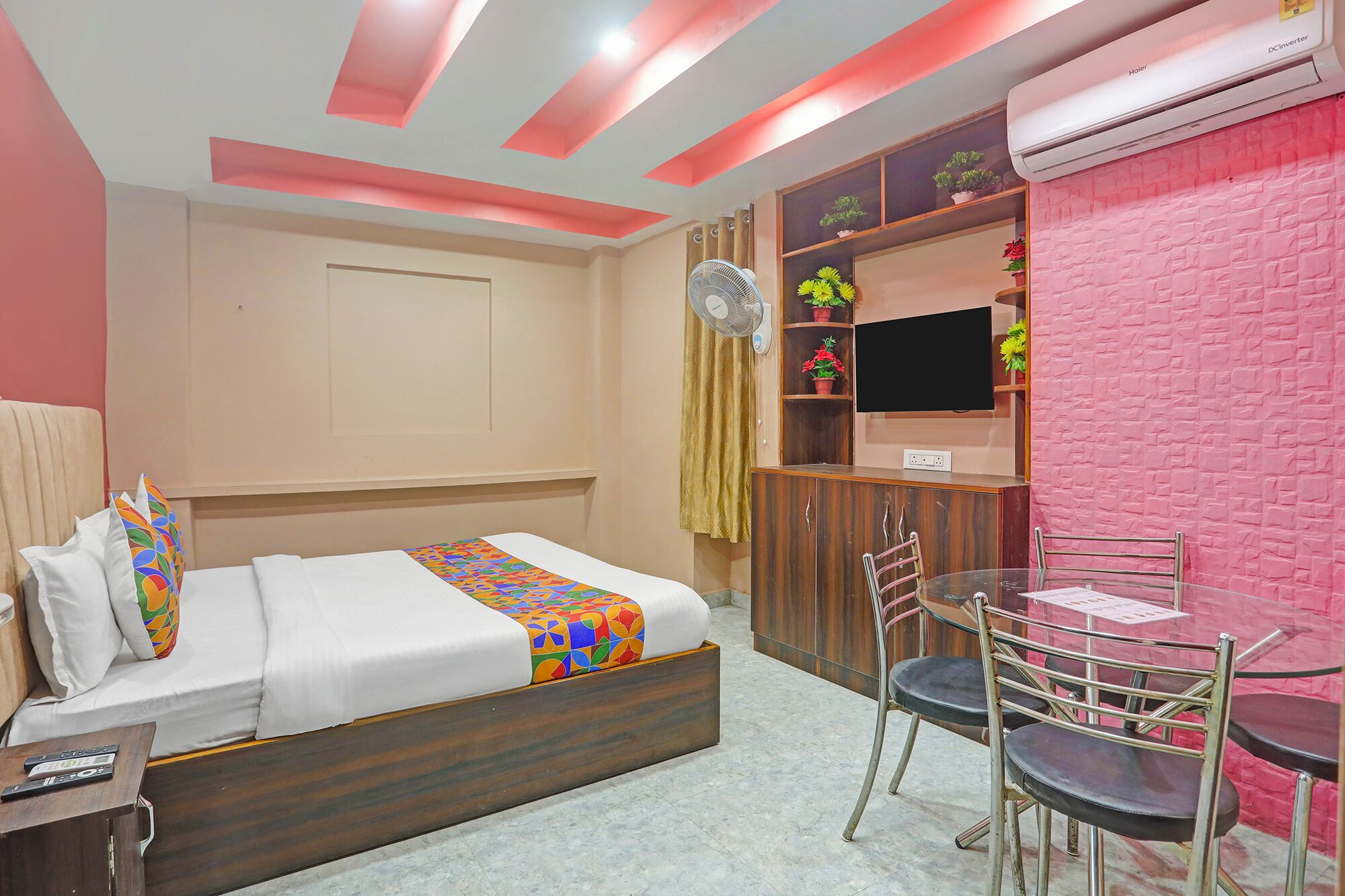 Habitación de hotel con cama, escritorio con silla, televisor y aire acondicionado instalado en la pared.