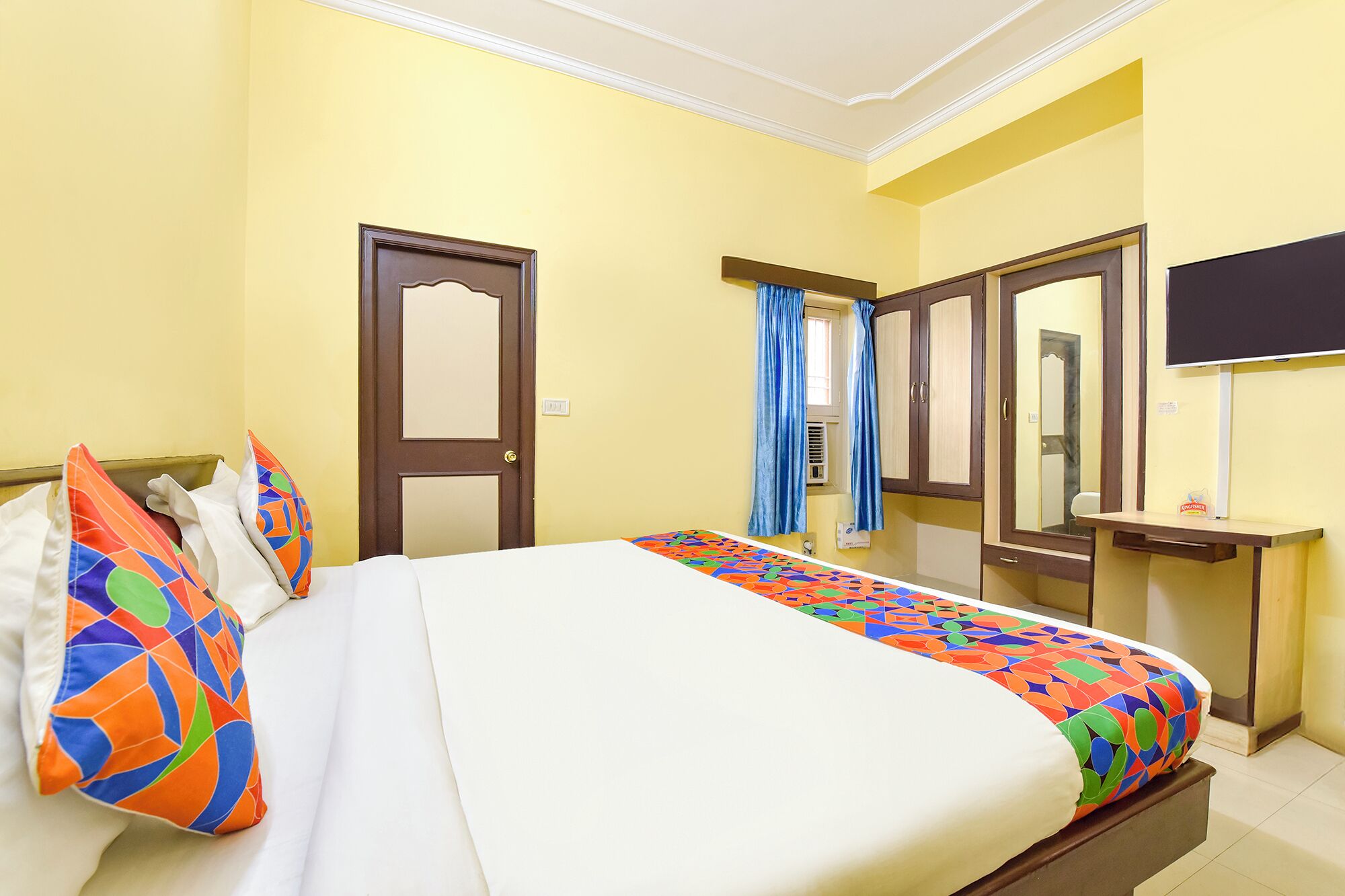 Una habitación de hotel con cama, escritorio, espejo y televisor.