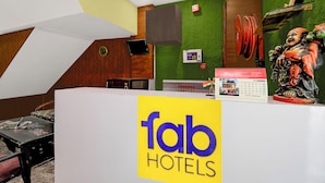 A reception desk with a 'fab hotels' sign, a clock, and a calendar on the wall. - Fabhotel Family Inn (Lucknow)