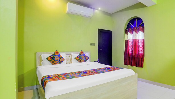 A bedroom with a bed, a window with curtains, an air conditioning unit, and a door. - Fabhotel Avante Palace (Ranchi)