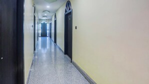 A long, narrow hallway with a polished floor, doors on both sides, and a ceiling with recessed lighting. - Fabhotel Avante Palace (Ranchi)