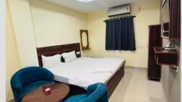 A hotel room with a bed, a desk, a chair, a ceiling fan, and an air conditioning unit.