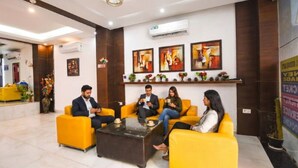 A lobby with yellow sofas, a coffee table, and artwork on the walls. - Fabhotel Clayton (New Delhi)