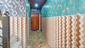 A narrow hallway with patterned walls and a tiled floor, leading to a wooden door. - Via Ayodhya Residency (Ayodhya)