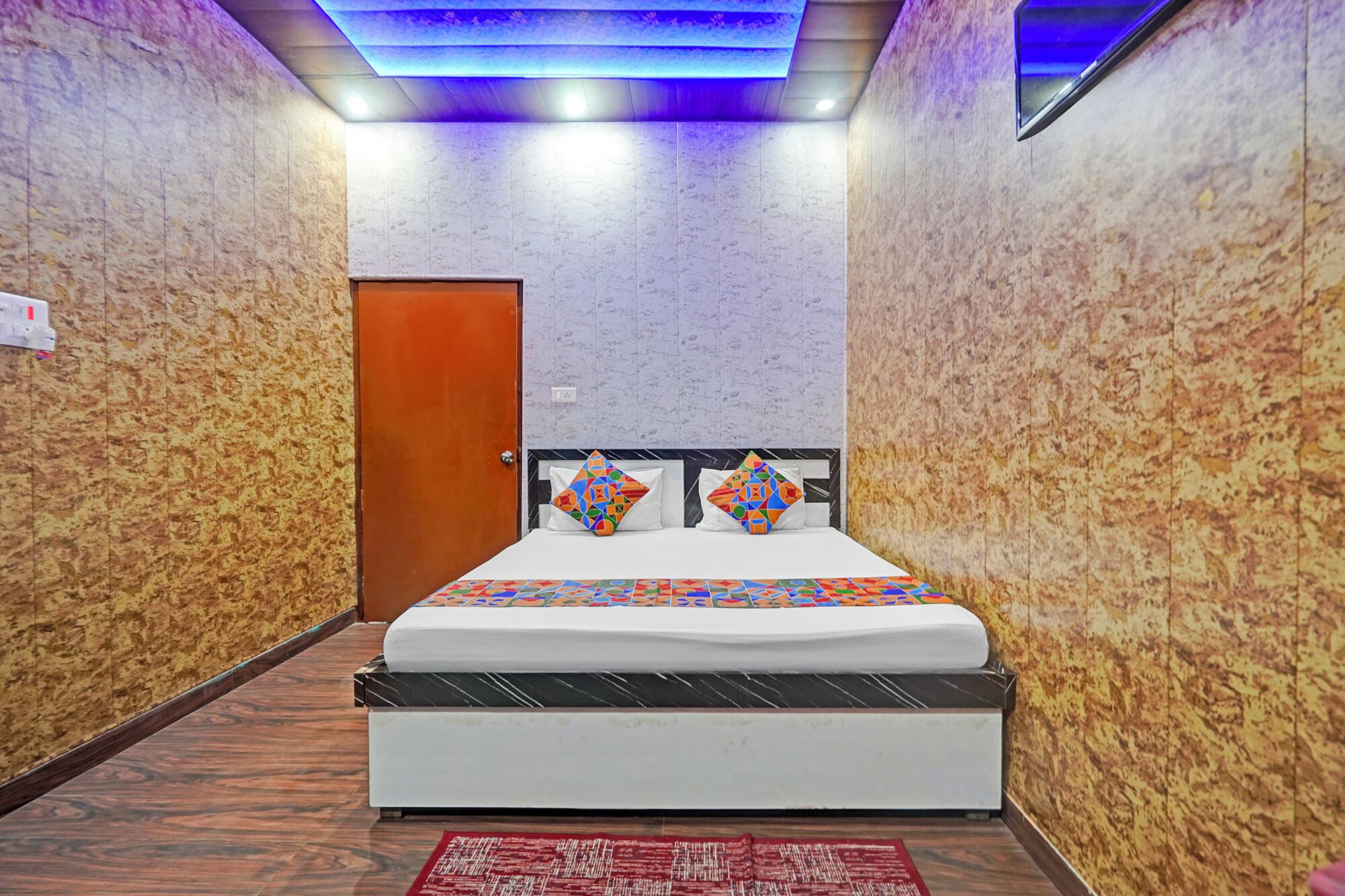 A hotel room with a bed, a wooden door, and patterned walls.
