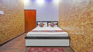 A hotel room with a bed, a wooden door, and patterned walls. - Via Ayodhya Residency (Ayodhya)