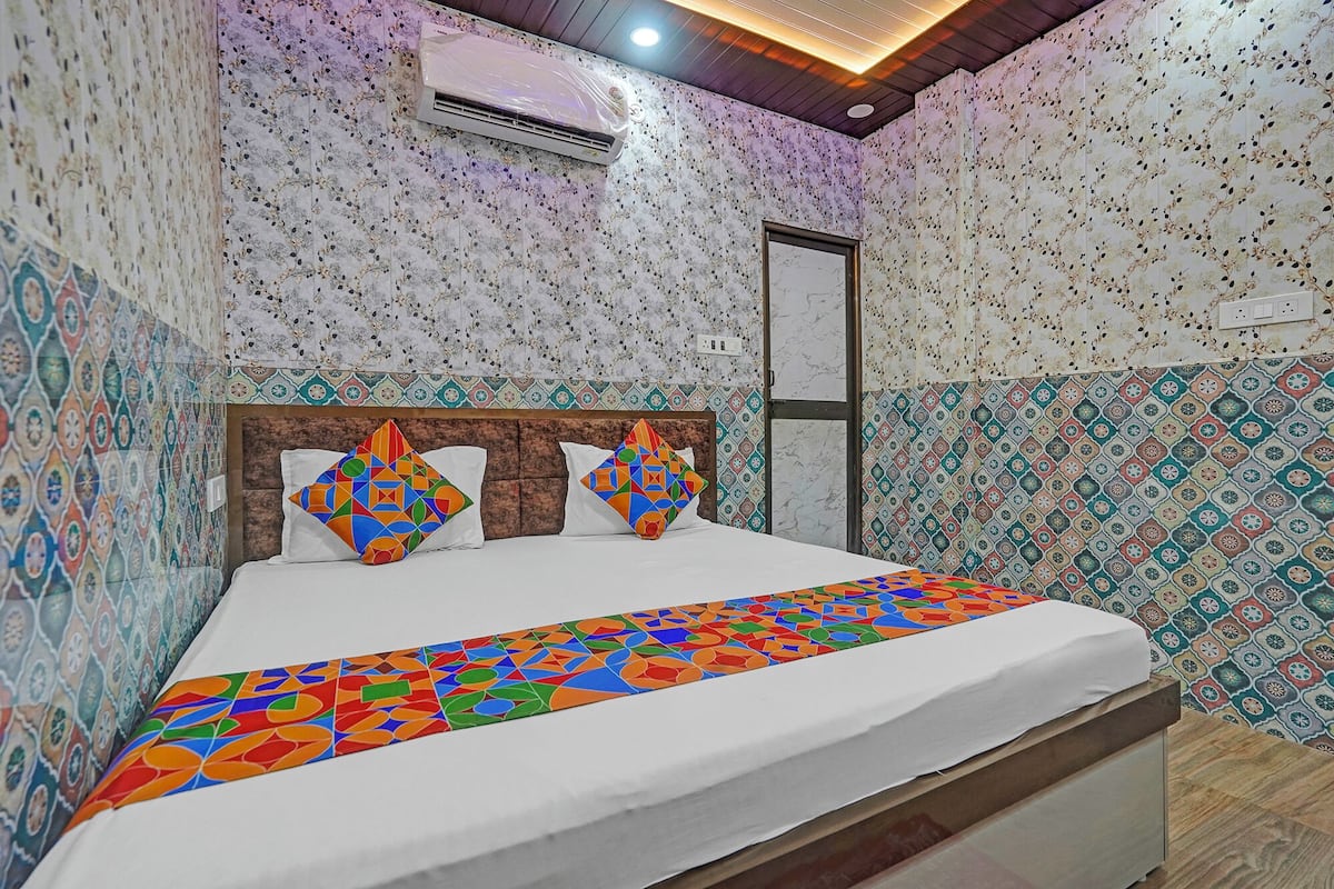 Une chambre à coucher avec un lit, un papier peint à motifs, un appareil de climatisation et un plafond en bois.
