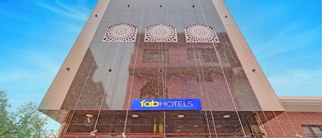 Um hotel com fachada moderna, um logotipo em destaque e uma entrada tradicional.