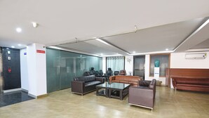 A modern waiting area with a glass partition, leather sofas, a coffee table, and a no smoking sign. - Fabhotel Laxmi Mahal (New Delhi)