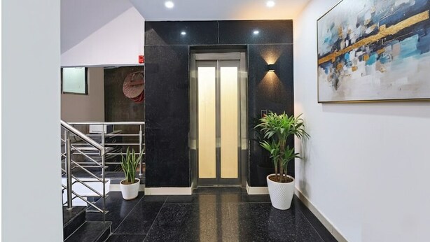 A modern lobby with a staircase, a reception desk, and two potted plants. - Fabhotel Laxmi Mahal (New Delhi)