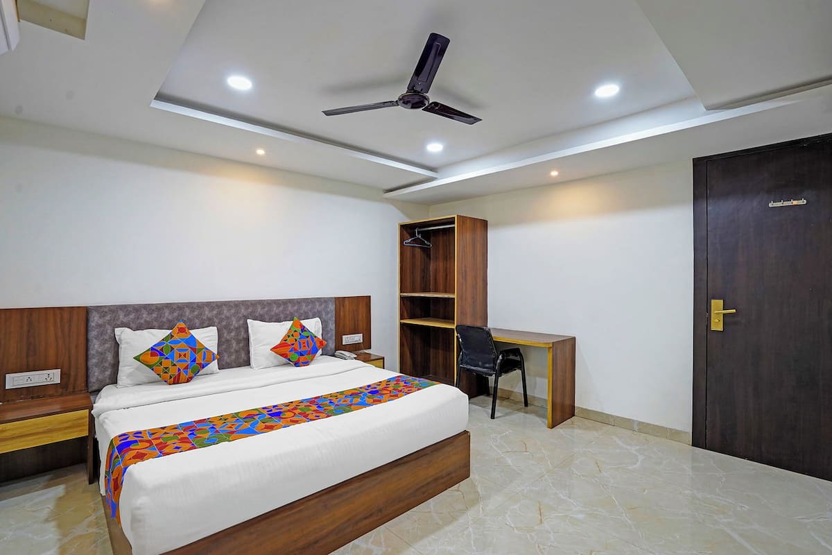 Une chambre moderne comprenant un lit, un bureau, une chaise, une armoire et un ventilateur de plafond.