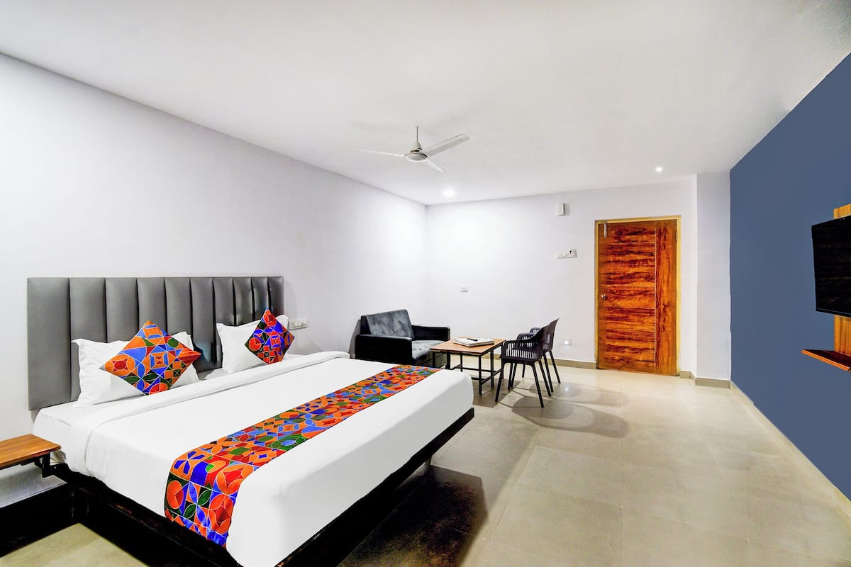 Una habitación de hotel moderna con una cama grande, un escritorio, una silla, un televisor y una puerta de madera.