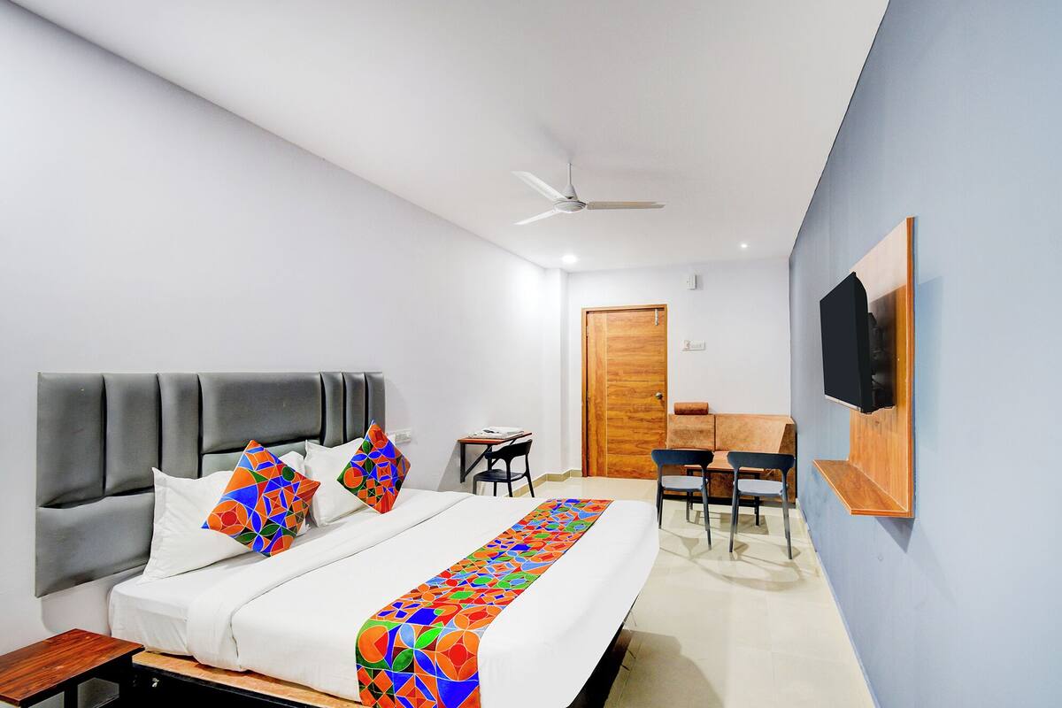Una habitación de hotel moderna con una cama, un escritorio, una silla y un televisor montado en la pared.