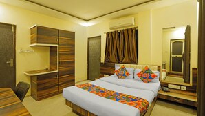 A hotel room with a bed, a wardrobe, a desk, a mirror, and an air conditioning unit. - Fabhotel Club Metro (Nagpur)
