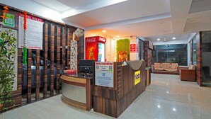 A hotel reception area with a wooden reception desk, a Coca-Cola refrigerator, and a Coca-Cola poster. There is a sign for hotel rules and a sign for the hotel club metro. - Fabhotel Club Metro (Nagpur)