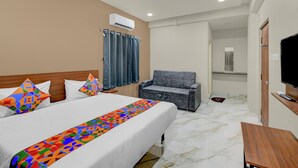 Ein Hotelzimmer mit einem Bett, einer Couch, einem Fernseher und einer Klimaanlage.