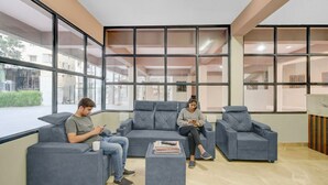 Ein Wartebereich mit grauen Sofas, einem Couchtisch und großen Fenstern mit Blick ins Freie.