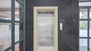 Ein Aufzug in einem Gebäude mit dunkel marmorierten Wänden und einer Glastür.