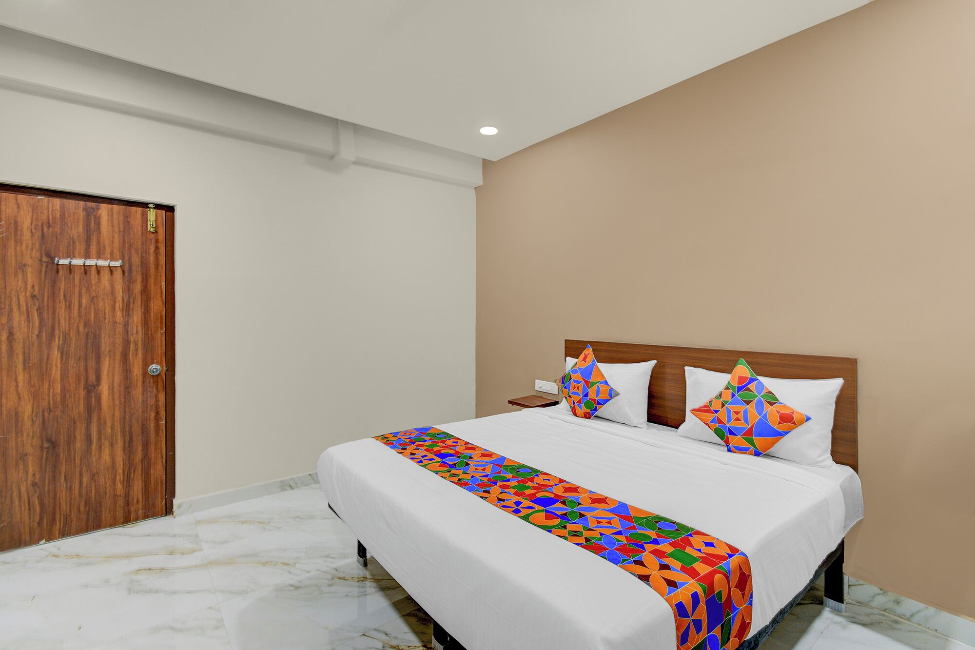Una habitación de hotel con cama, puerta de madera y suelo de mármol.