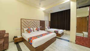 Habitación de hotel con dos camas, cabecera de madera, ventilador de techo, espejo y alfombra roja.