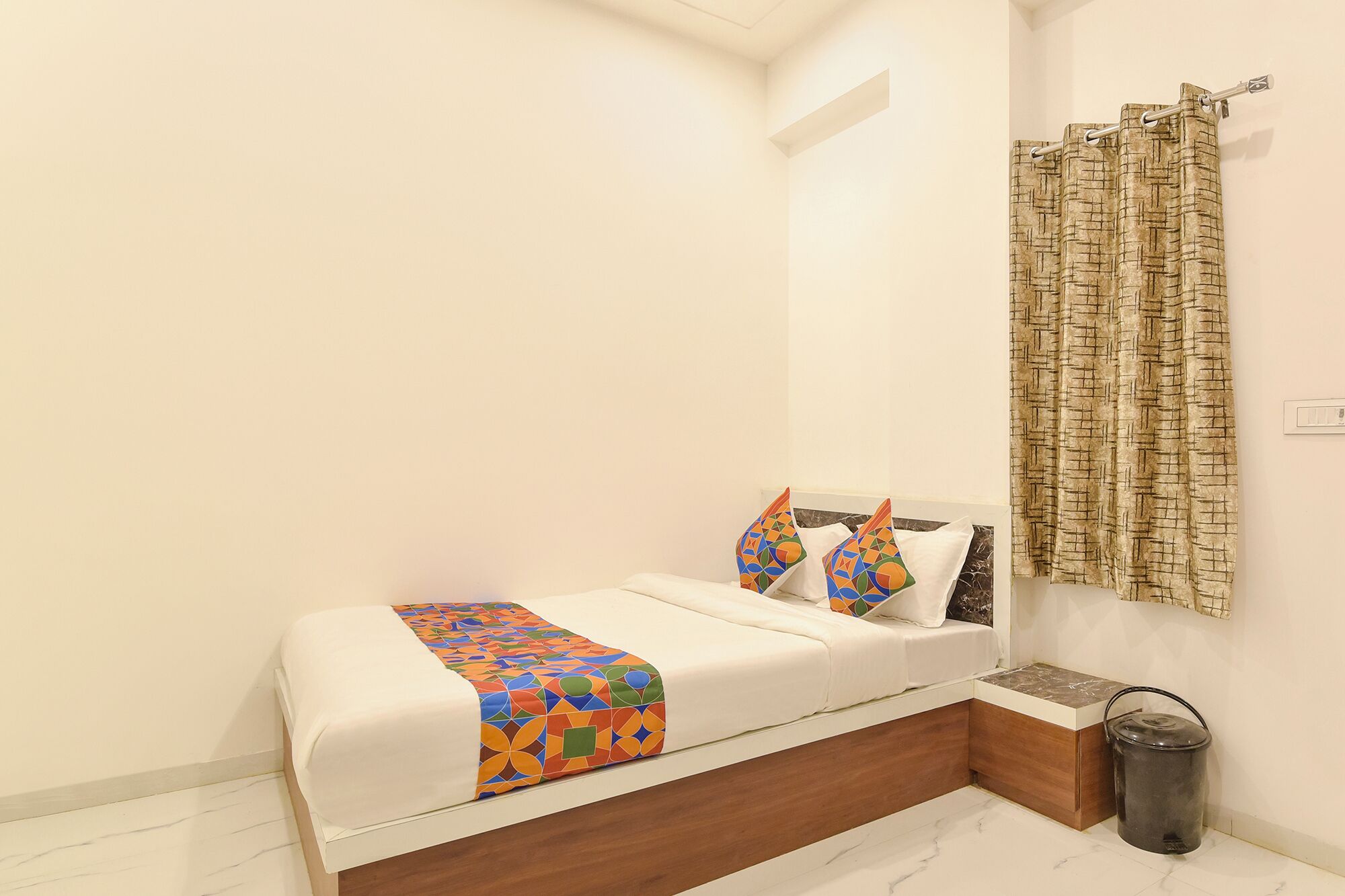 A small, modern bedroom with a single bed, a wooden bench, and a shower curtain.
