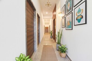 Un pasillo con una puerta de madera, una planta en maceta y cuadros en la pared.