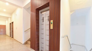 A modern elevator with a digital display, flanked by wooden panels and a handrail. - FabHotel Shree Radhey Shyam Palace - 500m Khatushyam Temple Khatoo (Khatoo)