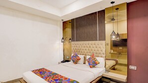 A bedroom with a bed, a bedside table, a mirror, and a ceiling fan. - Fabhotel Beach Front Resort (Calangute)